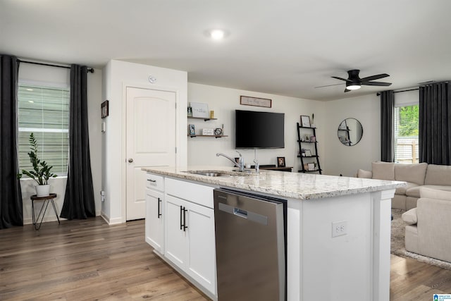 kitchen with light stone counters, open floor plan, white cabinets, dishwasher, and a sink