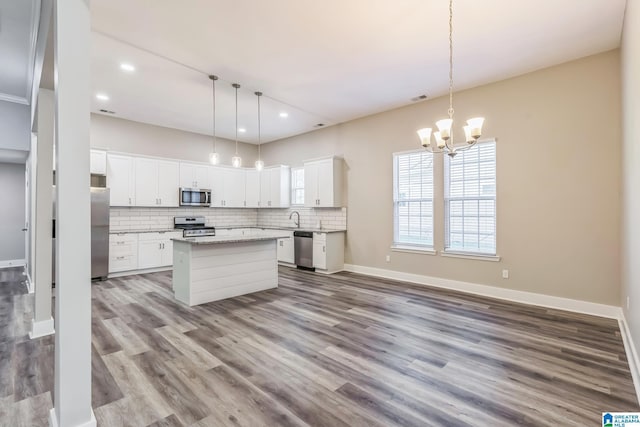 kitchen with recessed lighting, appliances with stainless steel finishes, wood finished floors, a notable chandelier, and backsplash