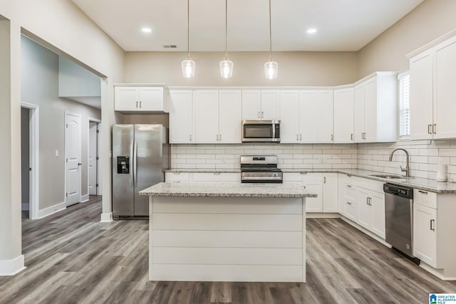 kitchen featuring tasteful backsplash, a center island, white cabinets, appliances with stainless steel finishes, and a sink