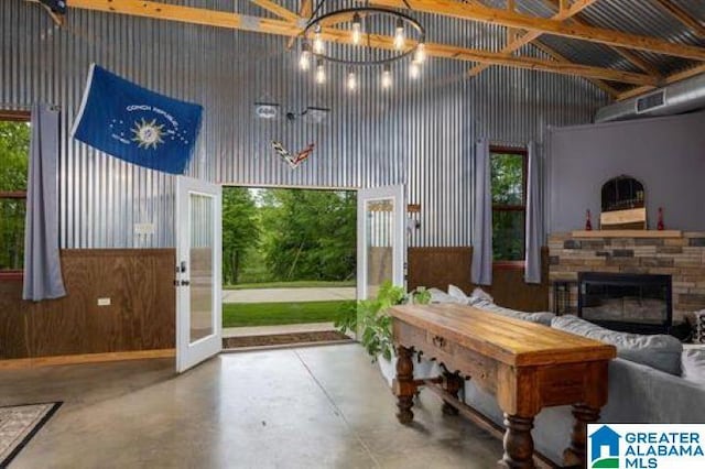 interior space featuring a stone fireplace, finished concrete floors, and a towering ceiling