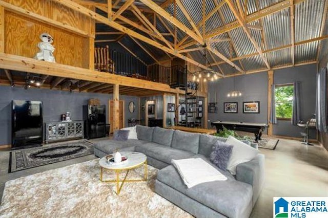 living room featuring high vaulted ceiling, concrete floors, and an inviting chandelier