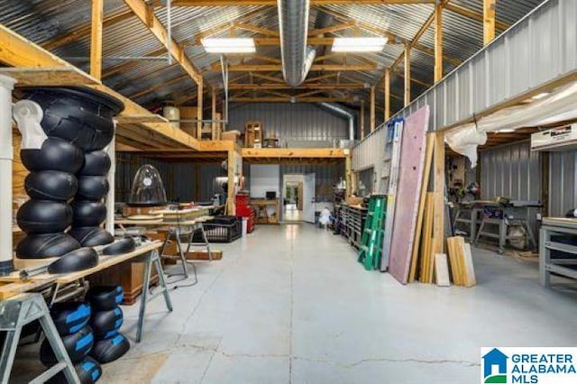 misc room featuring high vaulted ceiling, concrete floors, and a workshop area