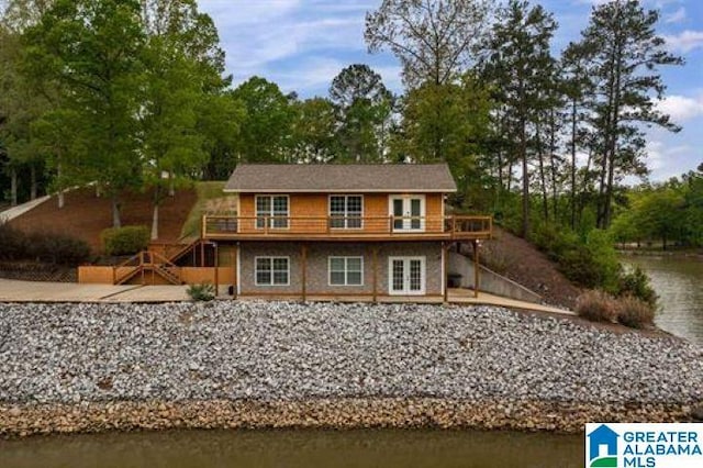 rear view of property with a deck with water view and stairs