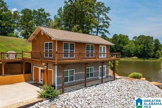 view of front facade featuring concrete driveway, a deck with water view, and a patio