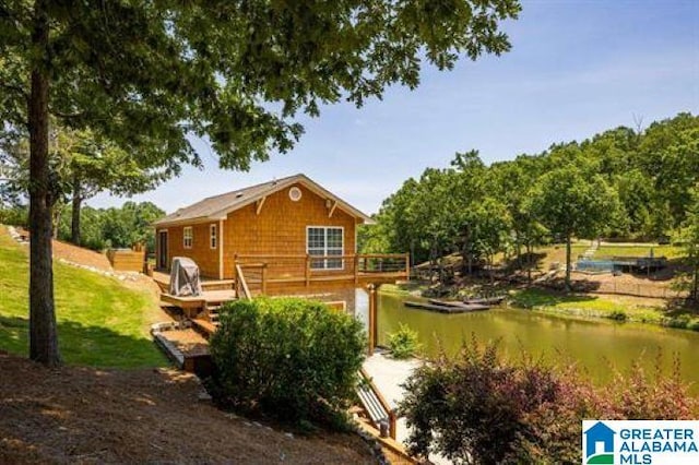 back of property with a deck with water view and a yard