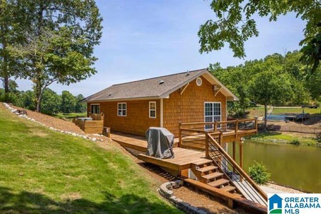 back of property featuring a deck with water view and a lawn
