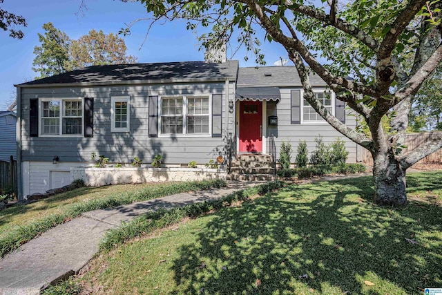 view of front facade featuring fence, entry steps, and a front lawn