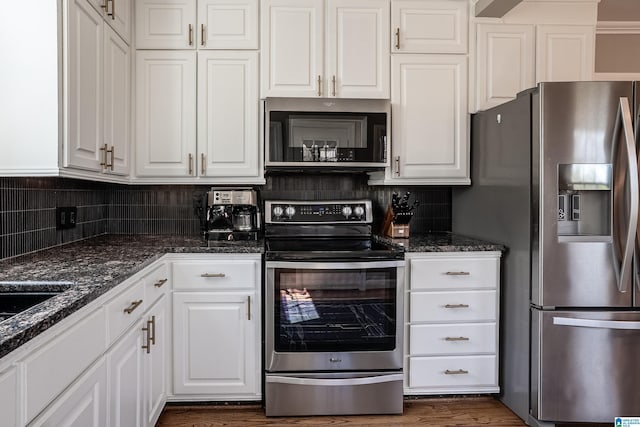 kitchen with appliances with stainless steel finishes, white cabinets, and backsplash