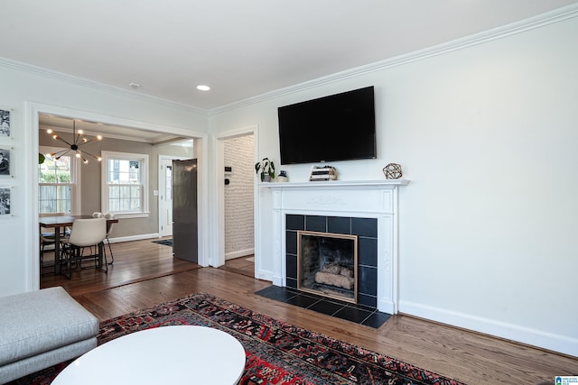 living area featuring dark wood-style flooring, a chandelier, crown molding, and baseboards