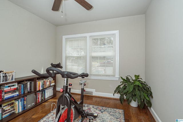 exercise room with baseboards, visible vents, wood finished floors, and ceiling fan