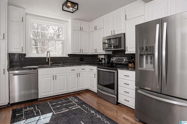 kitchen with dark stone countertops, appliances with stainless steel finishes, decorative backsplash, and white cabinetry