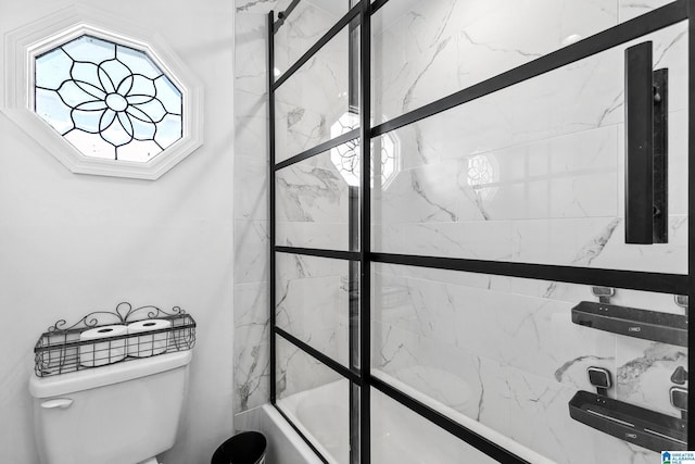full bathroom featuring toilet and bath / shower combo with glass door