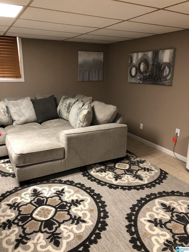 living area with light tile patterned floors, baseboards, and a drop ceiling