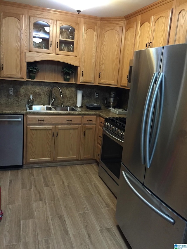 kitchen featuring a sink, backsplash, light brown cabinetry, and stainless steel appliances