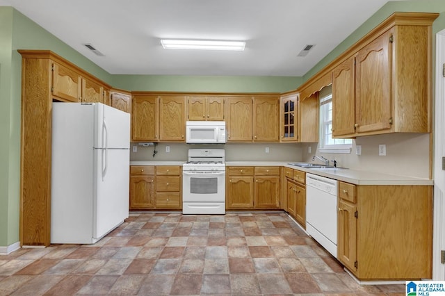kitchen with visible vents, a sink, white appliances, and stone finish flooring
