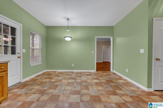 unfurnished dining area with baseboards and stone finish flooring