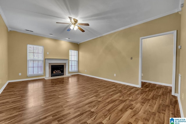 unfurnished living room with crown molding, a fireplace, a ceiling fan, wood finished floors, and baseboards