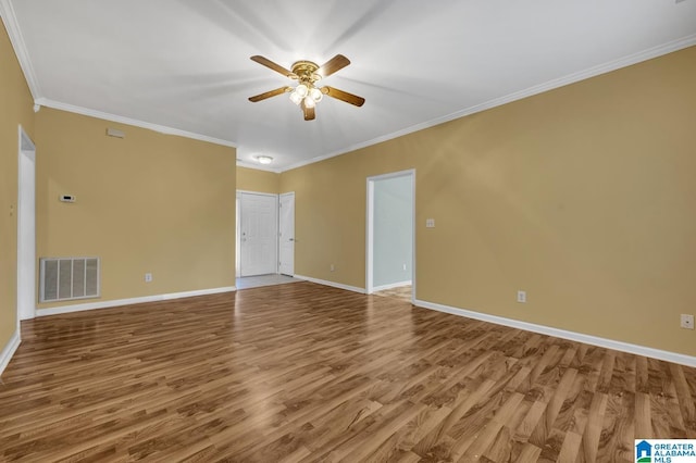 spare room with ornamental molding, a ceiling fan, visible vents, wood finished floors, and baseboards