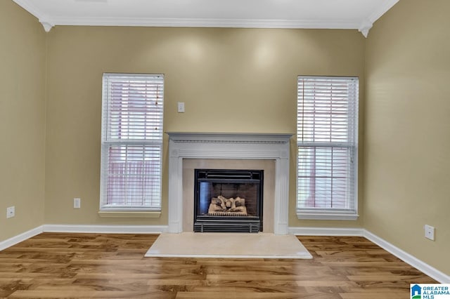 unfurnished living room featuring crown molding, wood finished floors, baseboards, and plenty of natural light