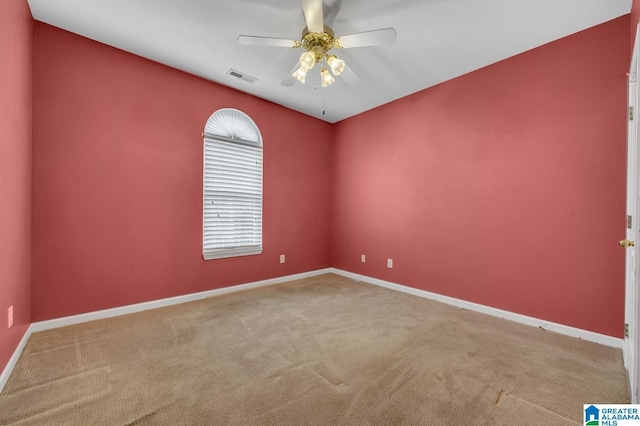 carpeted spare room featuring visible vents, ceiling fan, and baseboards