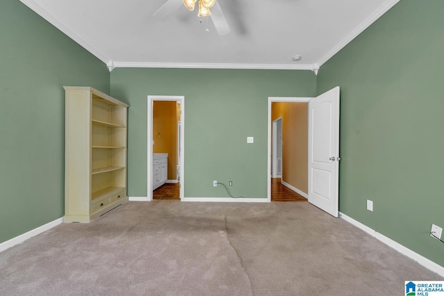unfurnished bedroom featuring baseboards, carpet flooring, ensuite bathroom, crown molding, and a ceiling fan