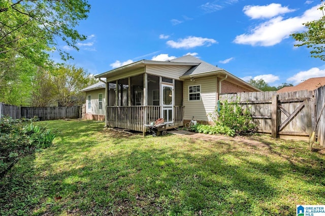 back of house featuring a sunroom, a yard, and a fenced backyard