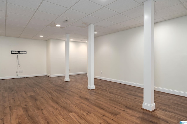 finished below grade area featuring wood finished floors, baseboards, and a paneled ceiling