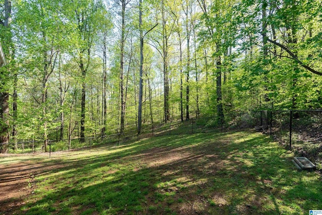view of yard featuring a fenced backyard and a forest view