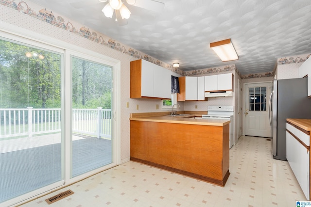 kitchen with white range with electric stovetop, freestanding refrigerator, a peninsula, under cabinet range hood, and light floors