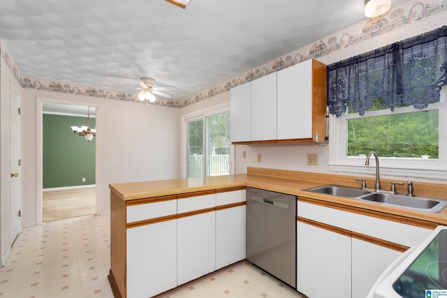 kitchen featuring dishwasher, a sink, a peninsula, range, and light floors