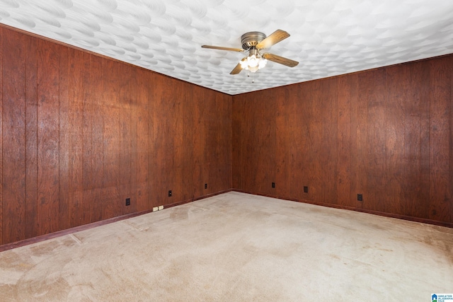 unfurnished room with light carpet, wood walls, and ceiling fan