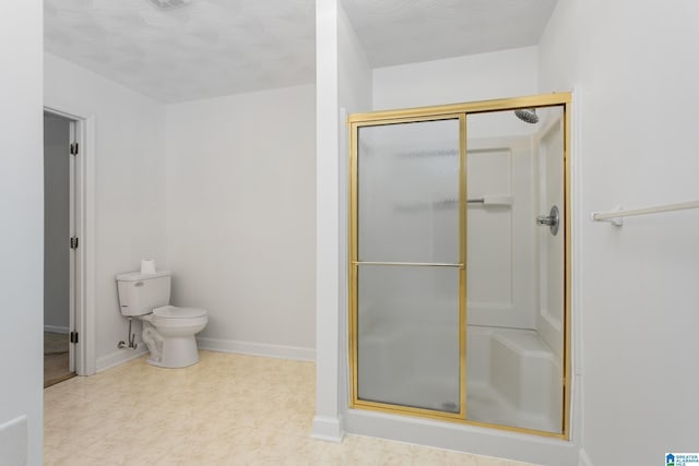 full bath with toilet, a stall shower, and baseboards