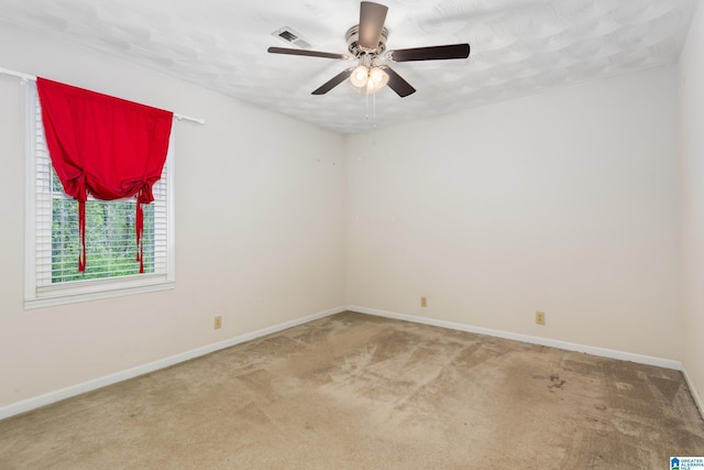 unfurnished room featuring carpet, visible vents, baseboards, and a ceiling fan