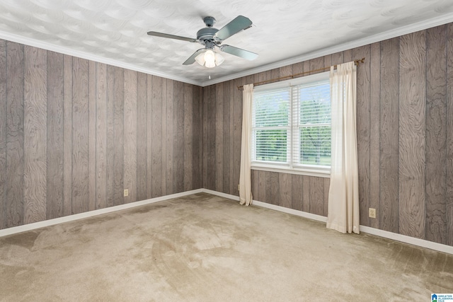 carpeted spare room featuring wooden walls, baseboards, and a ceiling fan