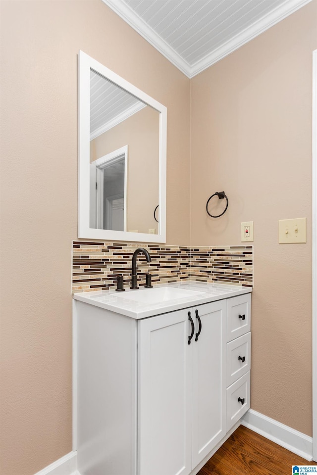 bathroom with tasteful backsplash, baseboards, crown molding, vanity, and wood finished floors