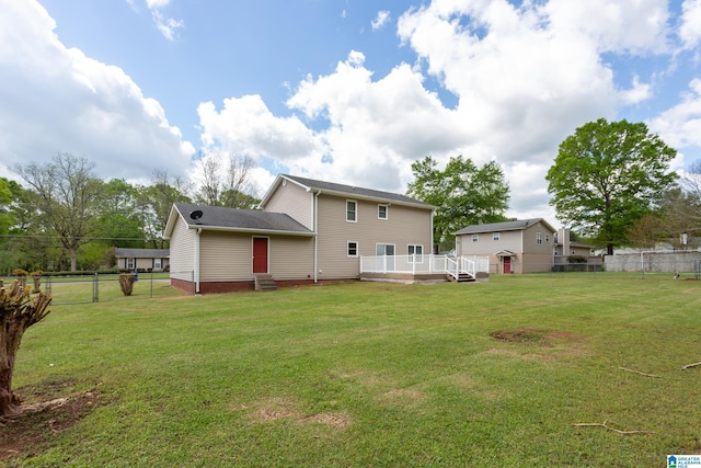 rear view of property with a yard, entry steps, fence, and a wooden deck