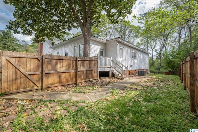view of side of property with central AC unit, a yard, and fence private yard