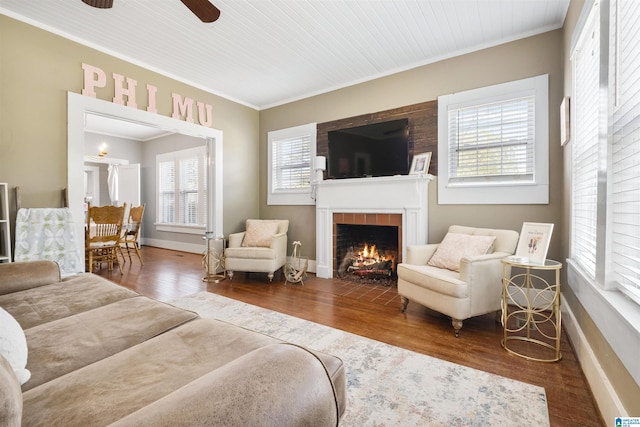 living room featuring crown molding, wood finished floors, a ceiling fan, and a tile fireplace