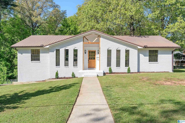 view of front of house featuring brick siding, a front yard, and metal roof
