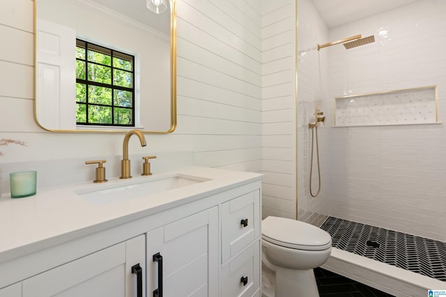 bathroom with ornamental molding, toilet, vanity, and tiled shower