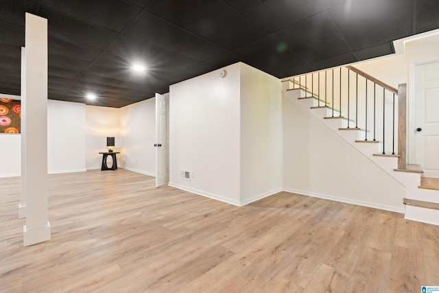 finished basement with stairs, wood finished floors, baseboards, visible vents, and recessed lighting