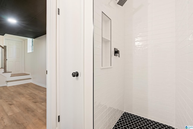 full bathroom featuring wood finished floors and tiled shower