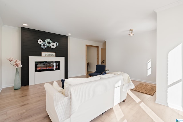 living area with crown molding, wood finished floors, a large fireplace, and recessed lighting