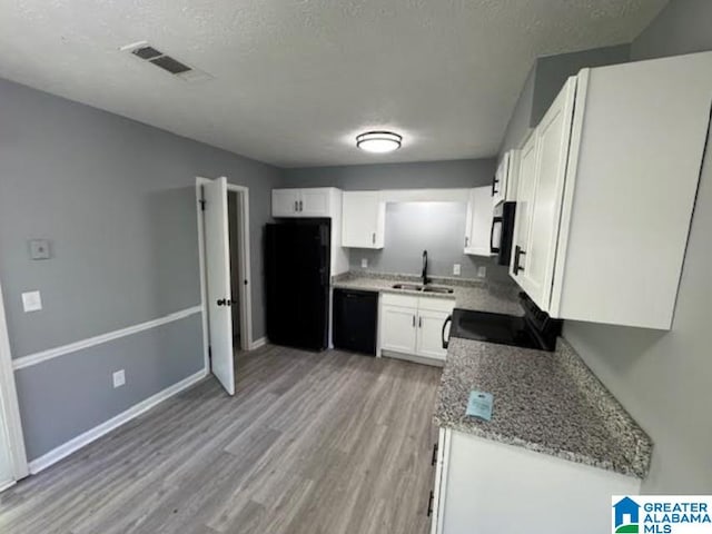 438 Henry St, Birmingham, AL 35214 - kitchen with visible vents, white cabinets, a sink, black appliances, and light wood finished floors