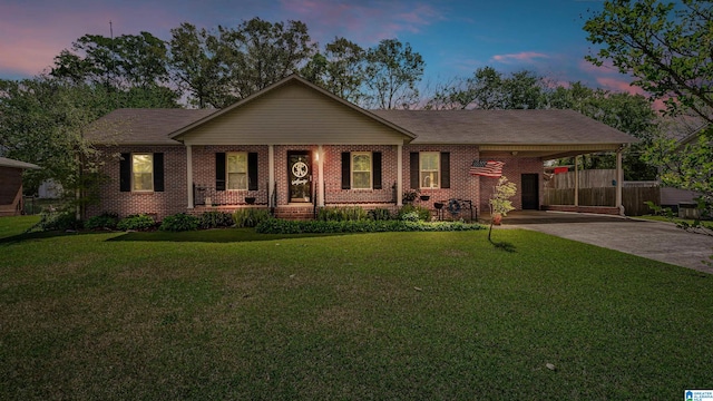 ranch-style house featuring concrete driveway, a yard, brick siding, and an attached carport