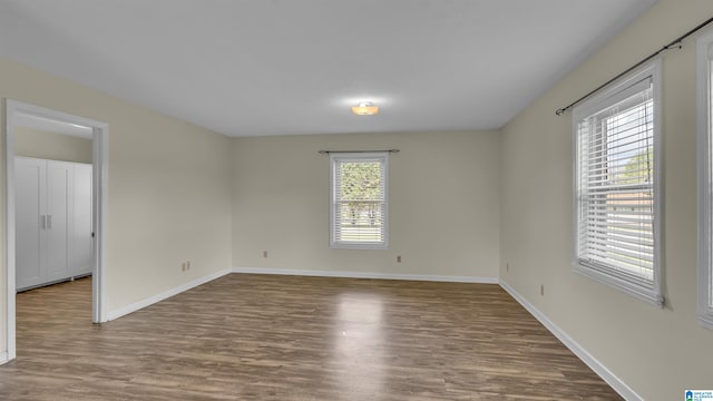 spare room featuring baseboards and wood finished floors