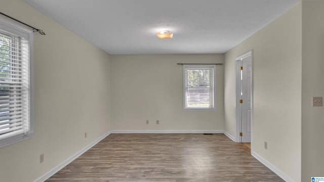 spare room featuring baseboards and wood finished floors
