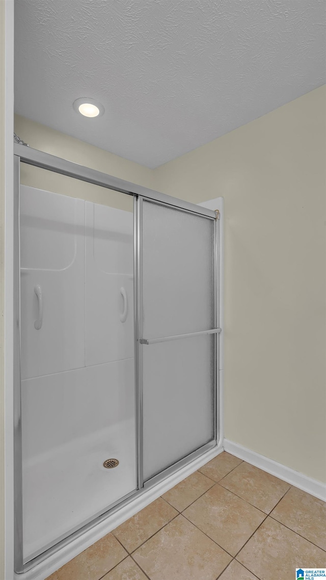 full bathroom with baseboards, tile patterned flooring, recessed lighting, a textured ceiling, and a shower stall
