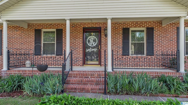 entrance to property with covered porch and brick siding