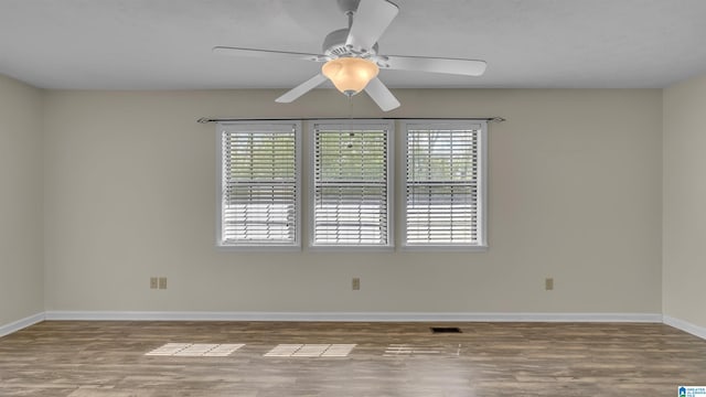 unfurnished room with wood finished floors, baseboards, a ceiling fan, and visible vents